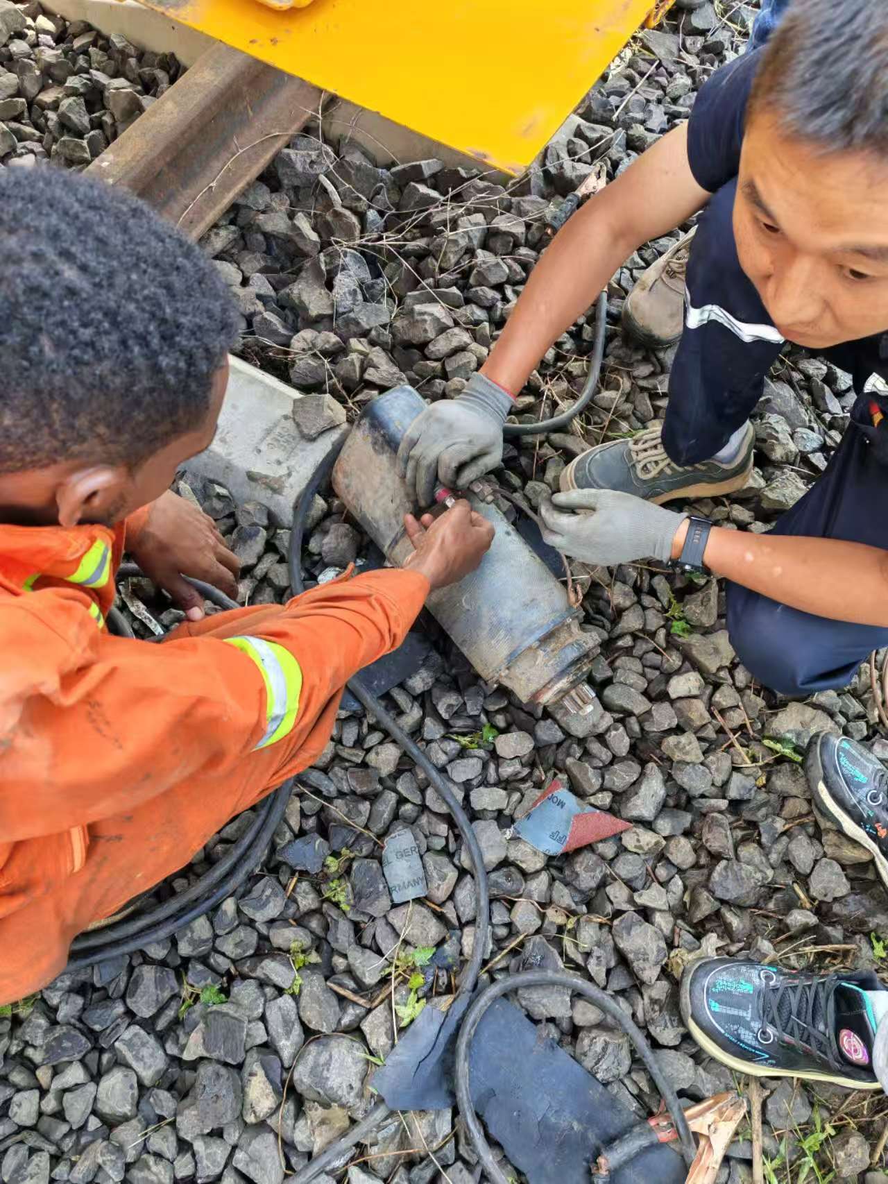 Railway technicians servicing a heavy mechanical component trackside